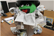 Oscar the Grouch figure in trash can with pumpkin for head. Trash, papers scattered around base