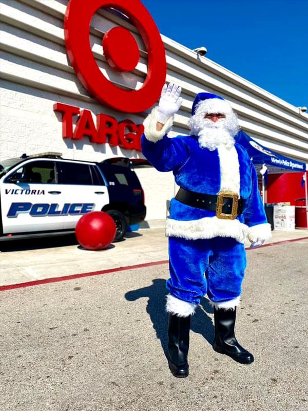 Blue Santa waves in front of Target. In the background are a parked squad car and a VPD canopy.
