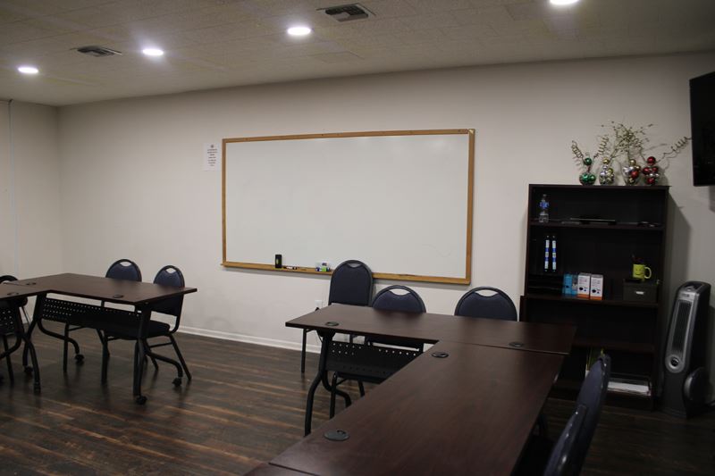 A classroom with long tables in a square and a whiteboard