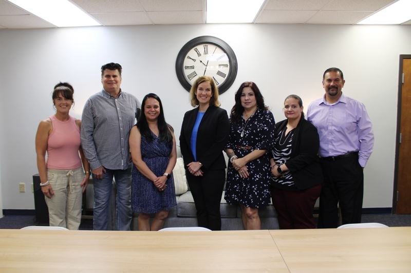 Group photo of seven people in an informal classroom area with a couch in the background.