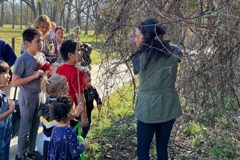 On the Athey Nature Trail walking path, a woman surrounded by children gestures to a tree