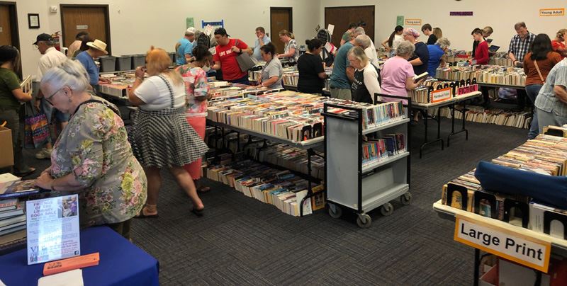 Large group of people browse makeshift shelves in the Victoria Public Library's Bronte room.