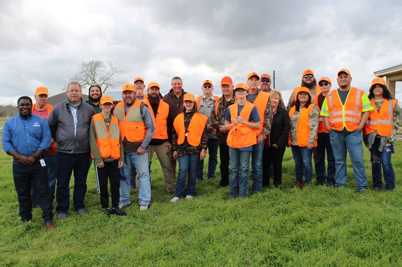 Large outdoor group photo of kids and adults, most of them in hunting gear