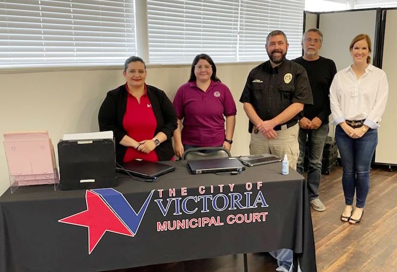 Group photo of people standing behind a table with a Municipal Court tablecloth.