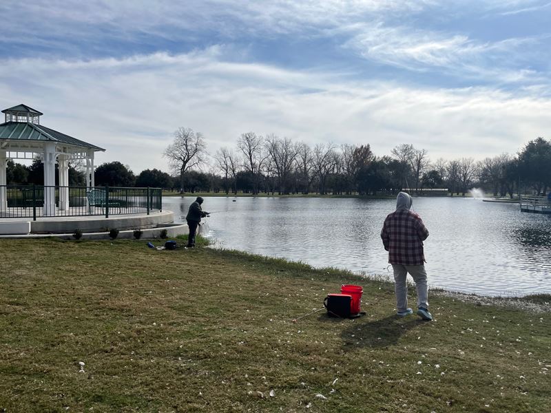 Two people fishing at the Riverside Park duck pond near the gazebo overlook