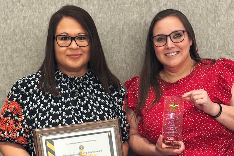 Two women, one holding a plaque and one holding a trophy