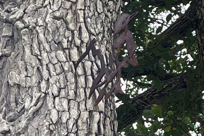A small metal cutout of a kingfisher mounted on a tree