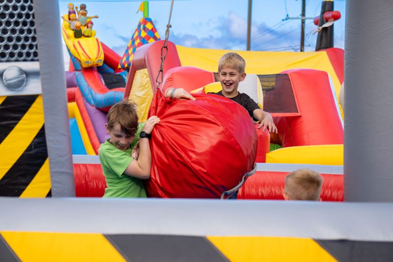 Young boys playing in a construction themed inflatable hanging onto a play wrecking ball