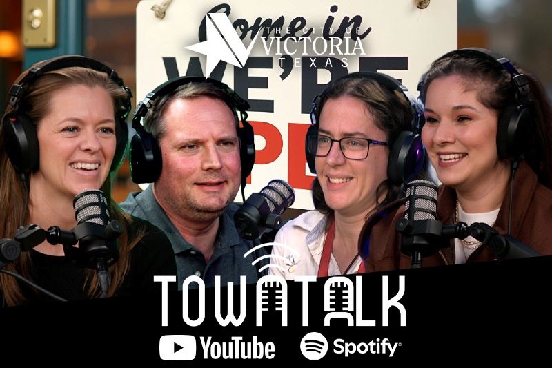 Four people smiling and laughing at podcast mics with graphic of a We're Open sign in the backgro