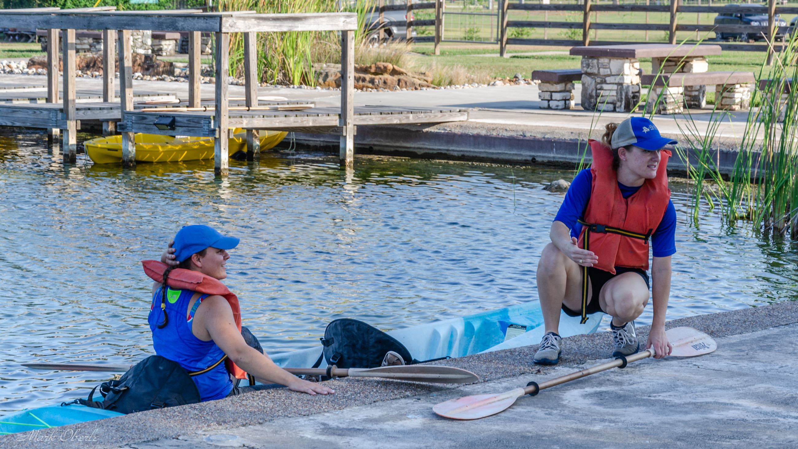 Woman on kayak with another woman on dock