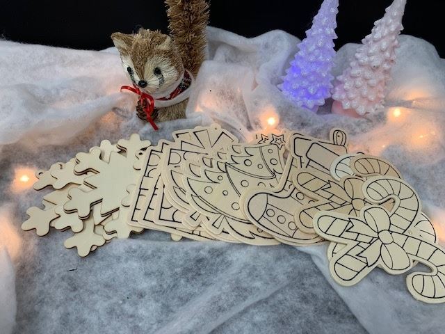 Wooden ornaments with Christmas designs are displayed in a faux snowscape with Christmas lights.