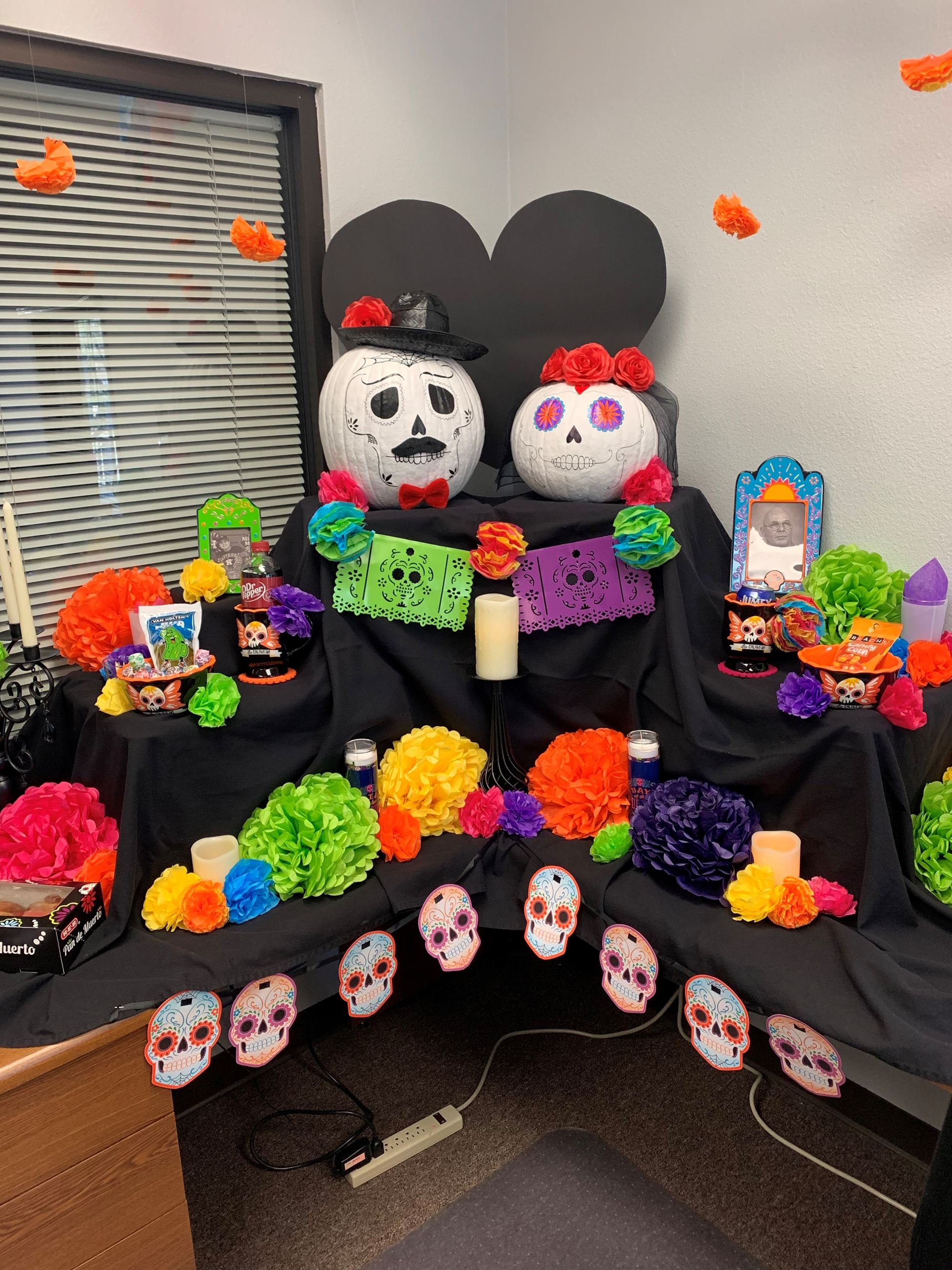 Mexican ofrenda with paper flowers, pumpkin sugar skulls, paper sugar skull cutouts, candles
