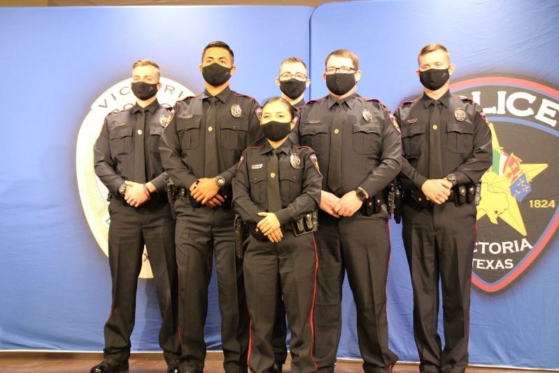 Six uniformed officers stand on stage in front of Victoria Police Department backdrop.