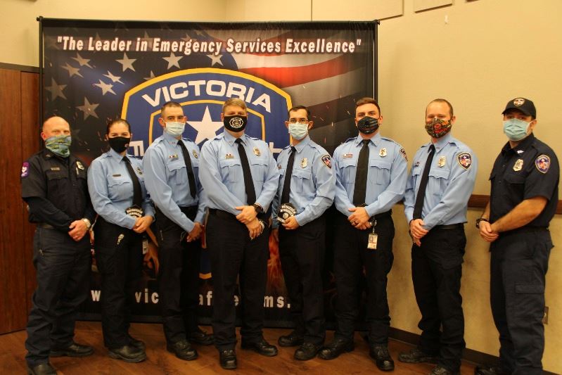 Firefighters in shirt-and-tie uniform stand in front of a backdrop