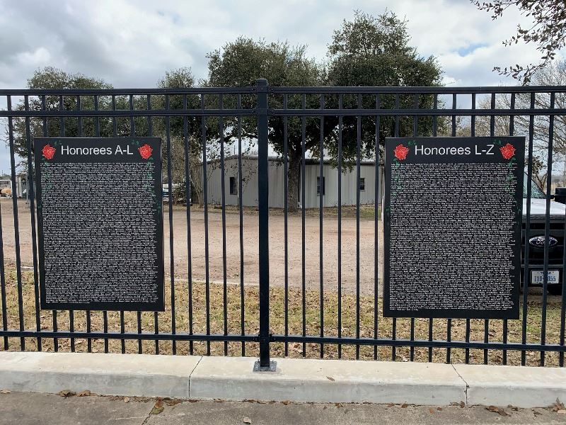 Two large plaques hanging on a black metal fence