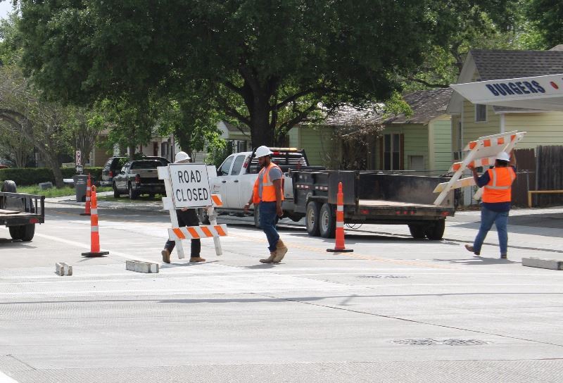 Construction workers move orange-and-white barricades from Crestwood near Dairy Treet
