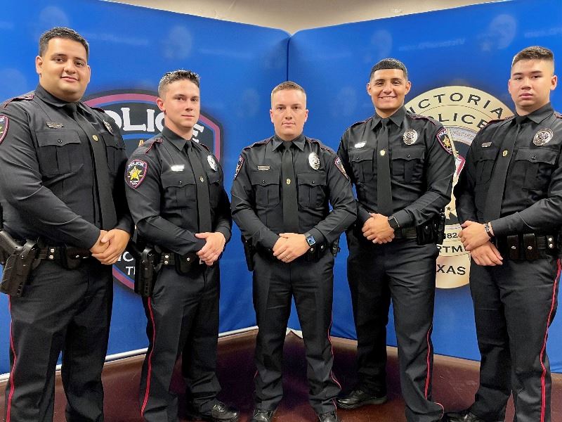 Five men in police uniform in front of police department backdrop