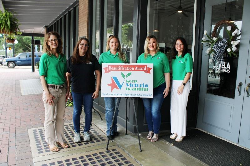 Five people pose with a sign that reads 