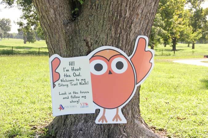 A cutout on a tree trunk with an owl character. Text reads 
