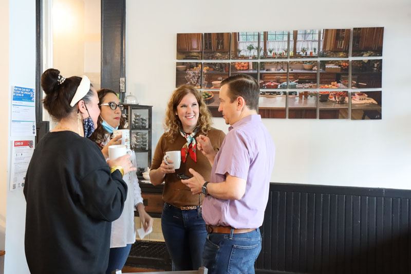 Four people holding coffee and talking