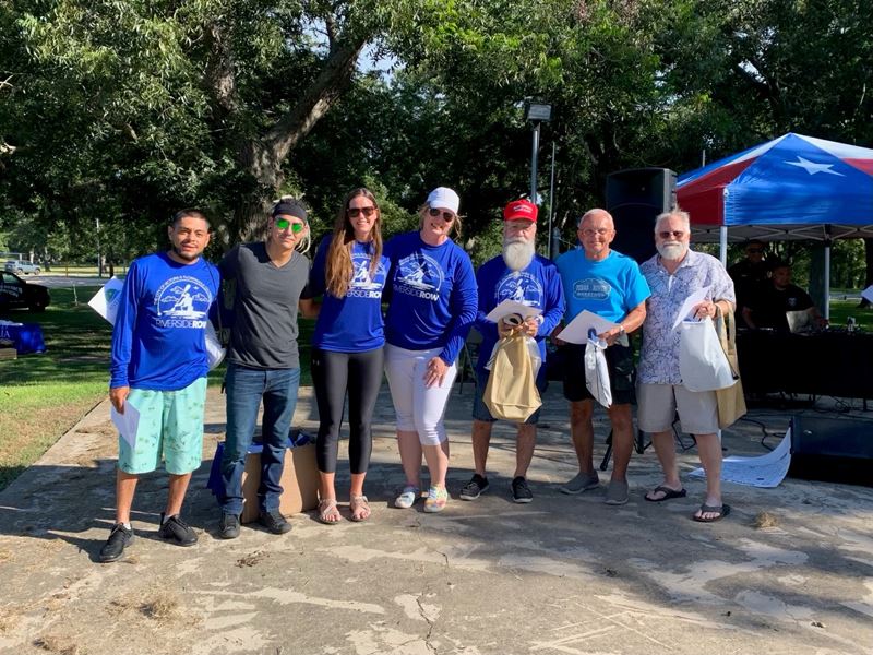 Group photo of seven people outdoors on a concrete pavilion in a park