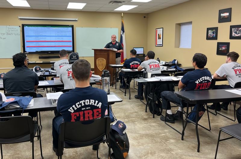 A man in a fire department shirt addresses a classroom