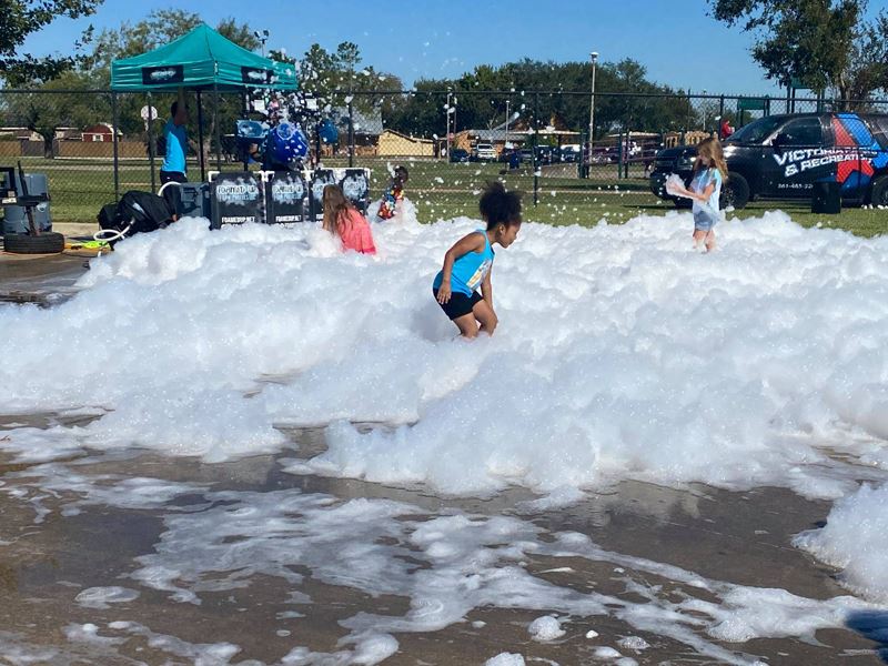Kids play in foam bubbles in a parking lot
