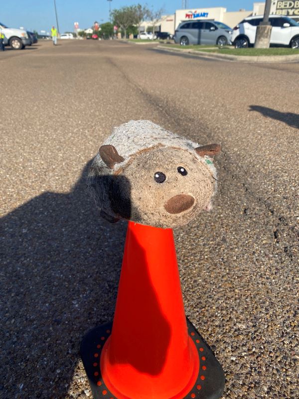 A plush toy resembling a fat sheep sits on top of a traffic cone