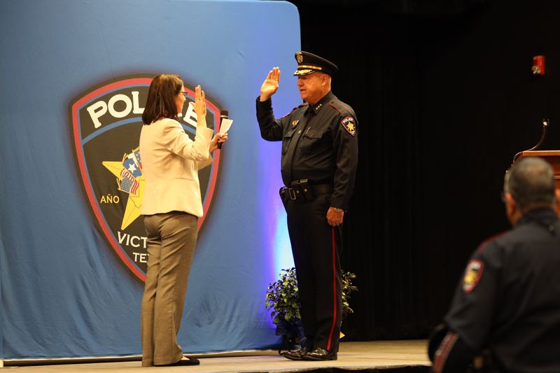 Man in police uniform raises his hand and is sworn in by a woman in front of a VPD backdrop