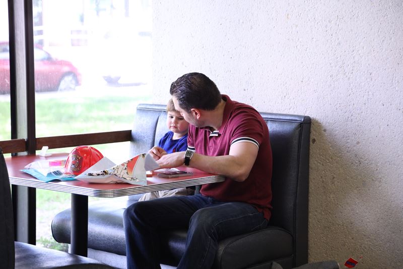 A man and a toddler sit together at a table and do a coloring activity. Opens in new window