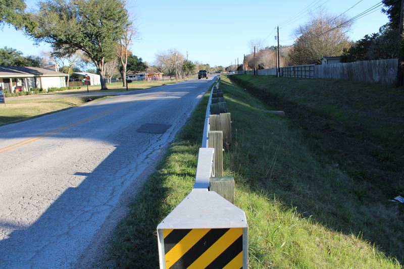 A damaged roadway with a wide open ditch next to it