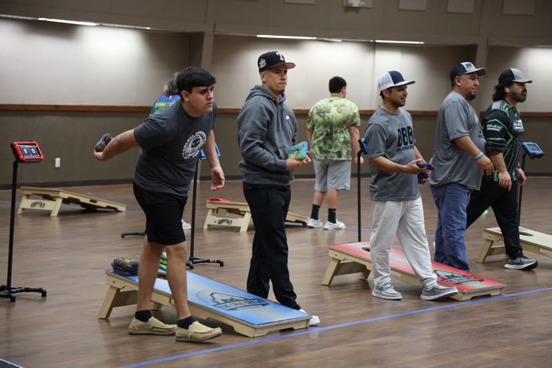 A line of people preparing to throw cornhole bags in the Community Center dome