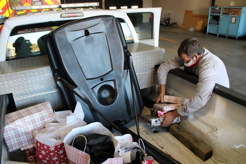 Man wearing Texas flag face covering places wrapped boxes in a truck bed next to a basketball hoop.