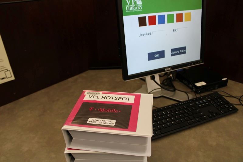 A stack of plastic VHS-style containers marked VPL Hotspot sit next to a computer.