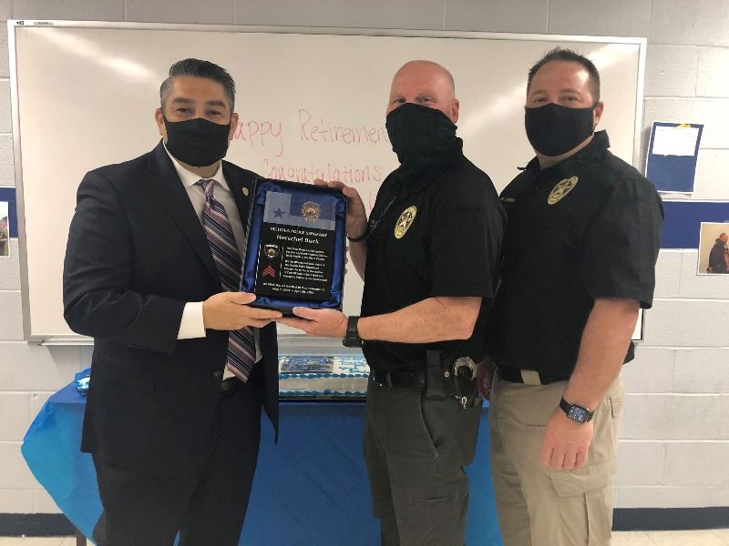 Two police officers present one police officer with a plaque