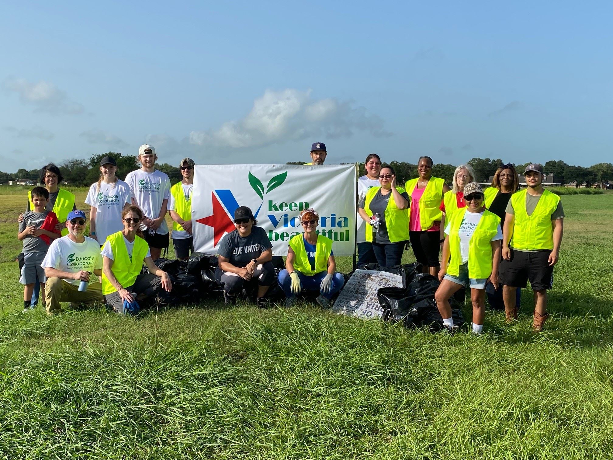 People in yellow safety vests pose for a group photo with KVB banner