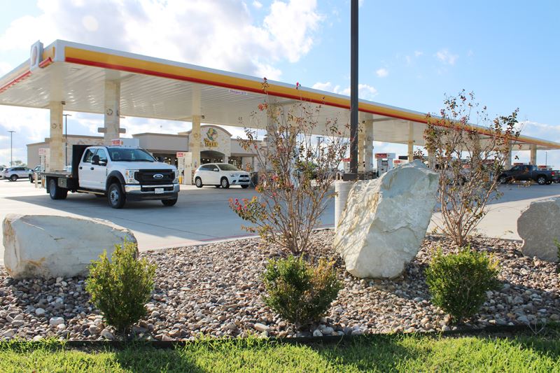 A bed of pebbles with boulders and shrubbery landscaping.