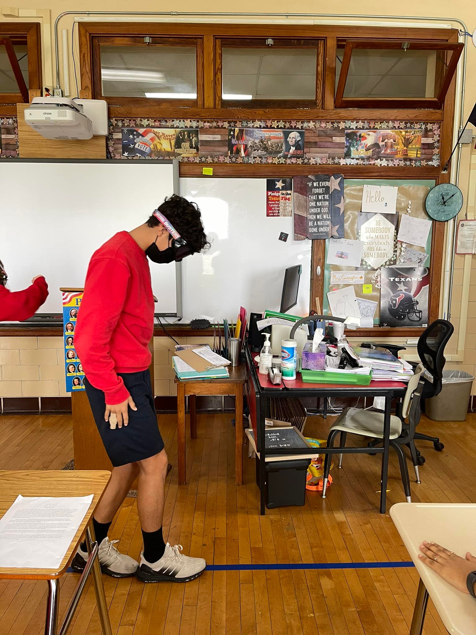 A student walks on a  straight line indicated by blue tape while wearing dark goggles.