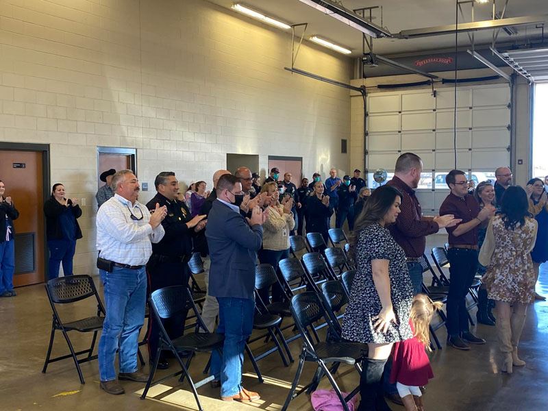 People stand and applaud in a makeshift auditorium in a fire station