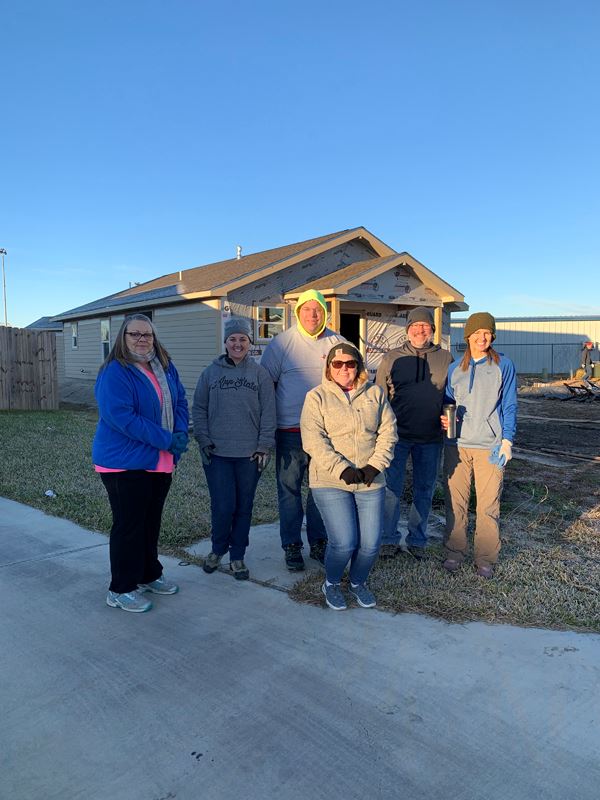 Group photo in front of an unfinished home