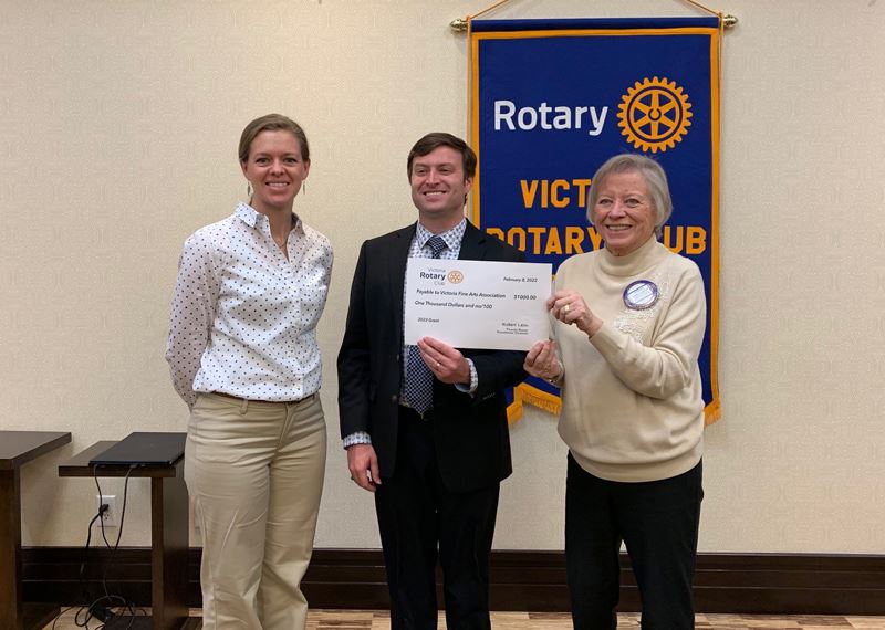 Three people at a certificate presentation. Banner behind them reads Victoria Rotary Club.