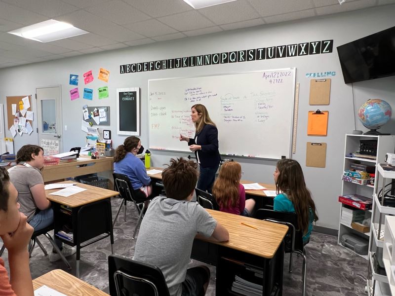 Woman stands in front of classroom and speaks to students