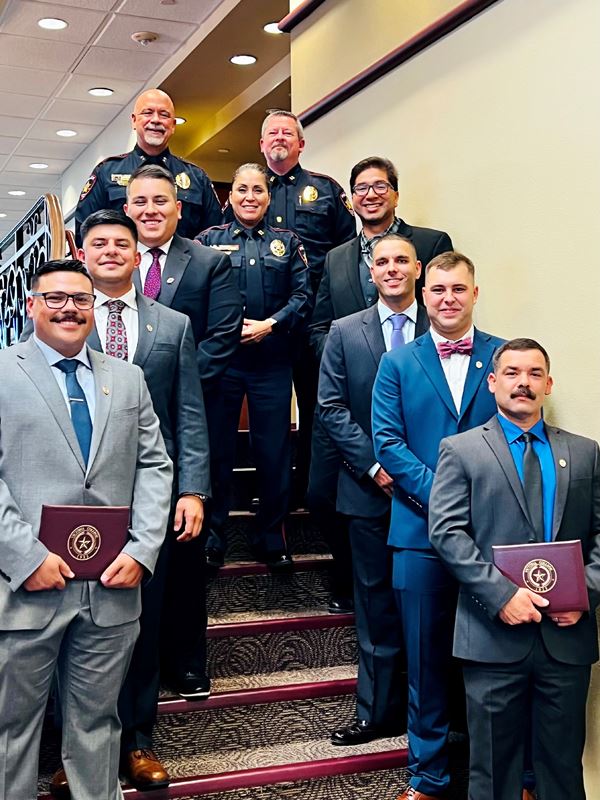 Ten people posing on stairs. The seven in front wear formal wear. The three in back wear uniforms.