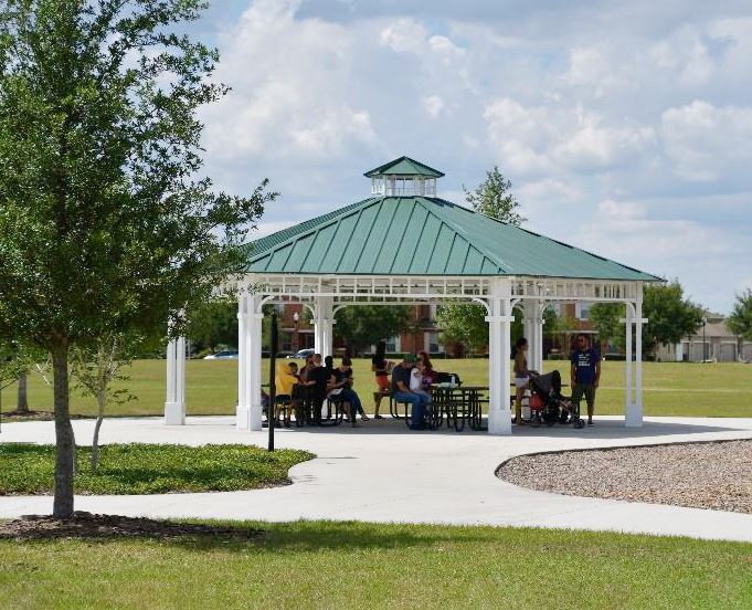 A white gazebo with a green hexagonal roof and a smaller roof above it.