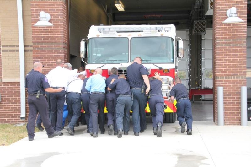 Team of fire fighters pushing a fire truck into the bay